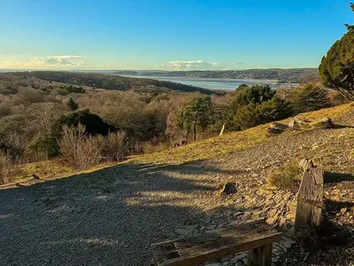 a bench on a hill with a view of the water at The Coach House, Yealand Redmayne perfect for a family in a rural setting, bring your dogs and horse in Beetham