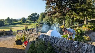 a man standing next to a stone wall with a fire place at The Coach House, Yealand Redmayne perfect for a family in a rural setting, bring your dogs and horse in Beetham