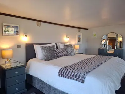 a bedroom with a large bed and a mirror at The Dairy, Yealand Redmayne in a rural setting, bring your dogs and horse in Beetham