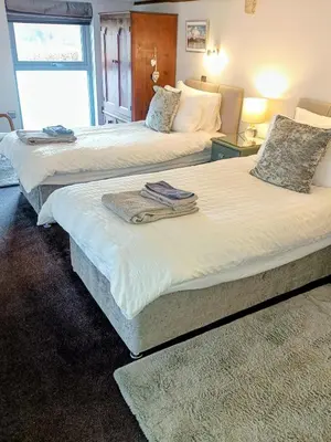 two beds in a hotel room with towels on them at The Dairy, Yealand Redmayne in a rural setting, bring your dogs and horse in Beetham