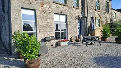 a stone building with a picnic table and a grill at The Dairy, Yealand Redmayne in a rural setting, bring your dogs and horse in Beetham