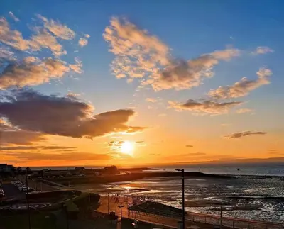 a sunset over a beach with the ocean at The Dairy, Yealand Redmayne in a rural setting, bring your dogs and horse in Beetham