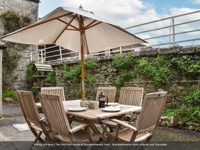 a wooden table with chairs and an umbrella at The Old Farmhouse, Yealand Redmayne, a characterful cottage in a rural setting in Beetham