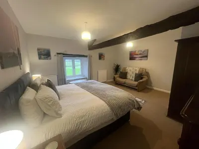 a bedroom with a bed and a chair in it at The Old Farmhouse, Yealand Redmayne, a characterful cottage in a rural setting in Beetham