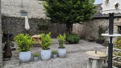 a courtyard with potted plants and a table and an umbrella at Corner Cottage, Yealand Redmayne, ideal family holiday, meet the resident animals in Beetham