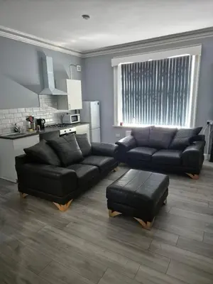 a living room with a black couch and a table at Holly House in Liverpool