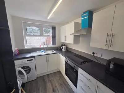 a kitchen with white cabinets and a sink and a dishwasher at 61 coniston street next to anfield street in Liverpool