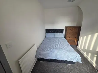 a small bedroom with a bed and a wooden dresser at 61 coniston street next to anfield street in Liverpool