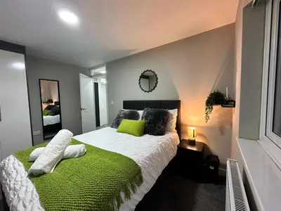 a bedroom with a large bed with a green blanket at Stylish 2BR Stay- Preston City in Preston