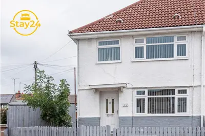 a white house with a fence in front of it at Surrey Suite in Wallasey
