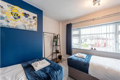 a bedroom with a bed and a blue wall at Surrey Suite in Wallasey
