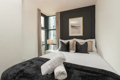a bedroom with a large white bed with black pillows at Luxury Liverpool City Centre Apartment with Balcony, Sleeps 8, Near Liverpool ONE and Royal Albert Docks in Liverpool