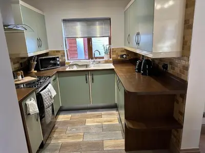 a kitchen with green cabinets and a sink at Comfy Stay Near City & Station in Preston