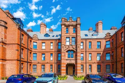 a large brick building with cars parked in front at Bright Flat with Wifi, Close to Beach! in Wallasey