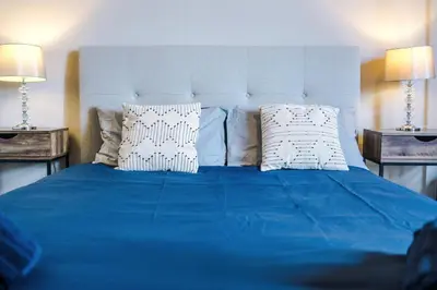 a blue bed with white pillows and two lamps at Bright Flat with Wifi, Close to Beach! in Wallasey