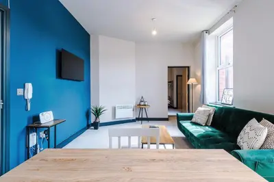 a living room with blue walls and a green couch at Bright Flat with Wifi, Close to Beach! in Wallasey