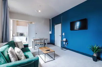 a living room with a green couch and a blue wall at Bright Flat with Wifi, Close to Beach! in Wallasey