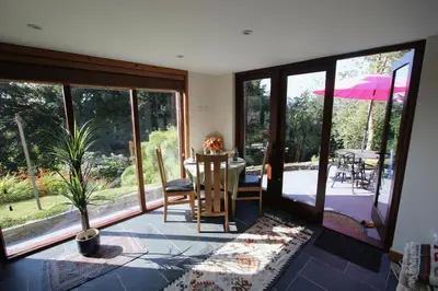 a living room with sliding glass doors and a table with a plant at The Rookery Sandside - Luxury Coastal Home South Lake District and Beaches