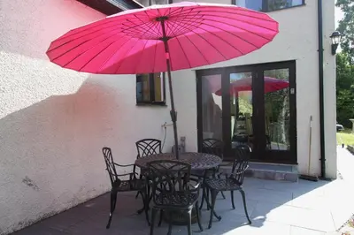 a table and chairs with a pink umbrella at The Rookery Sandside - Luxury Coastal Home South Lake District and Beaches