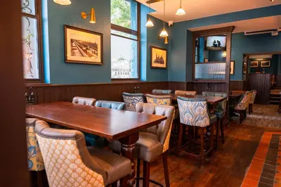 a restaurant with wooden tables and chairs and blue walls at The Royal Alfred - Opposite Central Train Station in Saint Helens