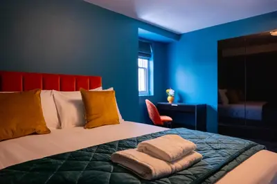 a blue bedroom with a bed with towels on it at The Royal Alfred - Opposite Central Train Station in Saint Helens