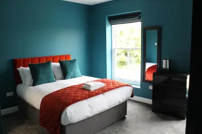 a bedroom with a bed with blue walls and a window at The Royal Alfred - Opposite Central Train Station in Saint Helens