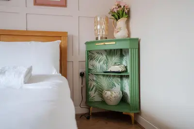 a green cabinet with vases on it next to a bed at 2 Bedroom Home with Garden and Free Parking in Litherland