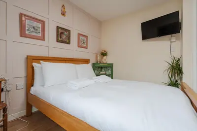a bedroom with a bed with white sheets and a flat screen tv at 2 Bedroom Home with Garden and Free Parking in Litherland