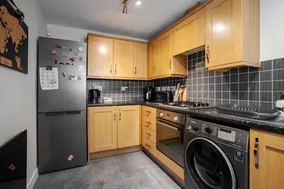 a kitchen with wooden cabinets and a black refrigerator at 2 Bedroom Home with Garden and Free Parking in Litherland