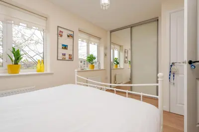 a white bedroom with a bed and a mirror at 2 Bedroom Home with Garden and Free Parking in Litherland