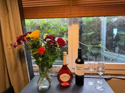 two bottles of wine and glasses on a table with flowers at Grange Cottage in Belmont
