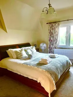 a bedroom with a large bed with towels on it at Grange Cottage in Belmont