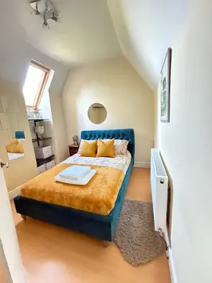 a bedroom with a bed with a blue head board at Grange Cottage in Belmont