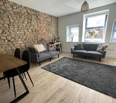 a living room with couches and a stone wall at High Street Apartment in Garstang