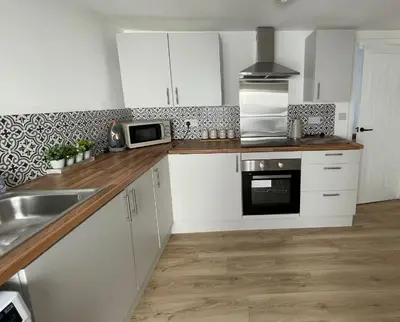 a kitchen with white cabinets and a sink and a microwave at High Street Apartment in Garstang