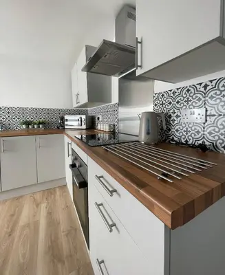 a kitchen with white cabinets and a wooden counter top at High Street Apartment in Garstang