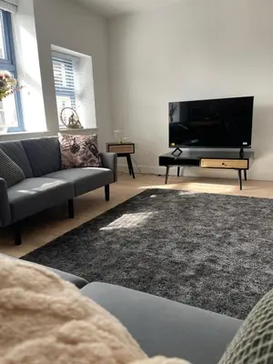 a living room with a tv and a couch and a piano at High Street Apartment in Garstang