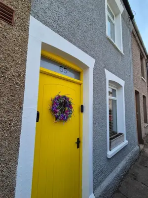 a yellow door on a building with a wreath on it at Driftwood Cottage in Askam in Furness