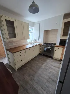 a kitchen with white cabinets and a sink and a stove at Driftwood Cottage in Askam in Furness