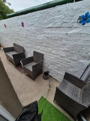 two wicker benches sitting next to a brick wall at Driftwood Cottage in Askam in Furness