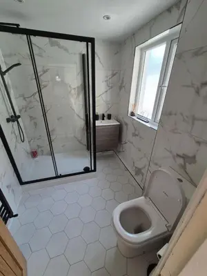 a white bathroom with a shower and a toilet at Driftwood Cottage in Askam in Furness