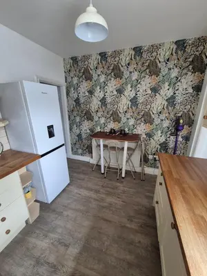 a kitchen with a table and a refrigerator at Driftwood Cottage in Askam in Furness