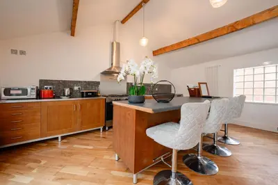 a kitchen with a counter with two chairs and a table at Luxury stay in Central Southport in Southport