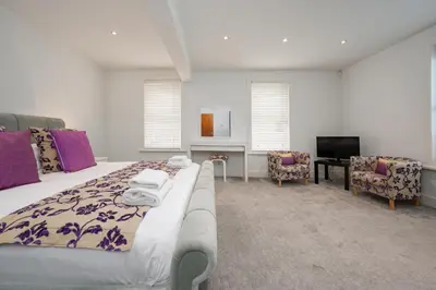 a bedroom with a bed and a tv and chairs at Luxury stay in Central Southport in Southport