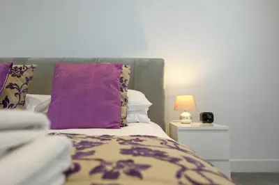 a bedroom with a bed with purple pillows and a lamp at Luxury stay in Central Southport in Southport
