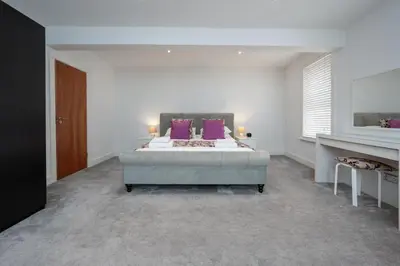 a bedroom with a large bed with purple pillows at Luxury stay in Central Southport in Southport