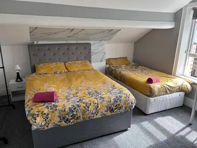a bedroom with two beds with yellow and pink sheets at Green-Lodge Triple Double & Single Rooms Near LFC Anfield Free Street Parking 24-7 in Liverpool