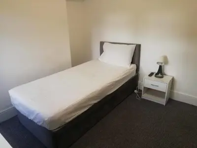 a bedroom with a bed and a lamp on a night stand at Green-Lodge Triple Double & Single Rooms Near LFC Anfield Free Street Parking 24-7 in Liverpool