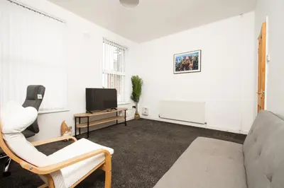 a living room with a couch and a tv at Cosy 2BR Flat Near Anfield & Goodison, Liverpool in Liverpool