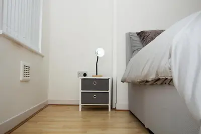 a bedroom with a bed and a night stand with a lamp at Cosy 2BR Flat Near Anfield & Goodison, Liverpool in Liverpool